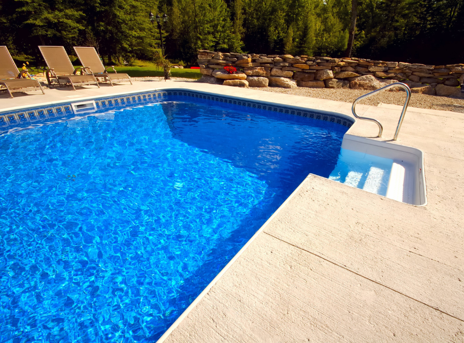 fiberglass pool with a stone wall in the background